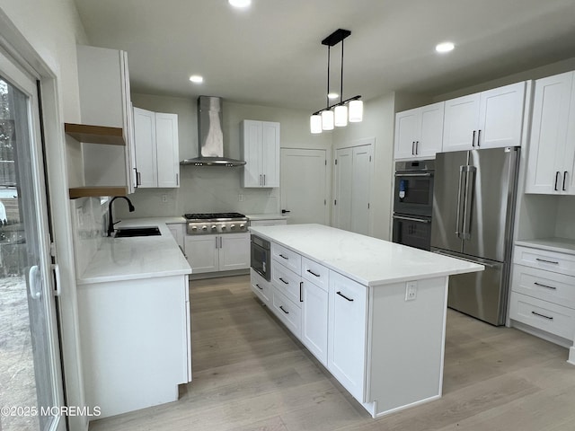 kitchen with white cabinetry, stainless steel appliances, a center island, wall chimney range hood, and sink