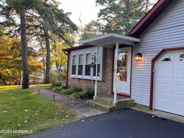 property entrance featuring a garage and a lawn