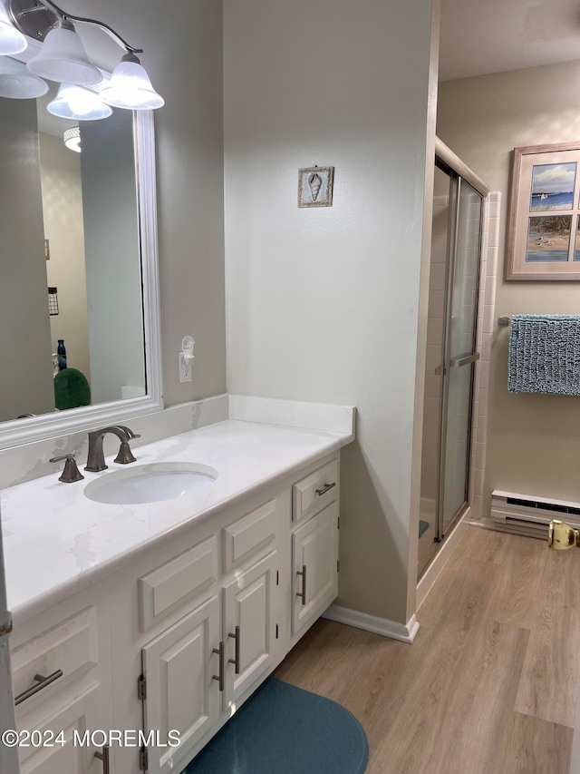 bathroom with vanity, baseboard heating, hardwood / wood-style flooring, and a shower with door