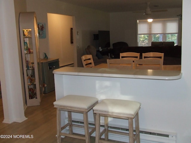 kitchen featuring hardwood / wood-style floors, ceiling fan, a kitchen bar, and kitchen peninsula