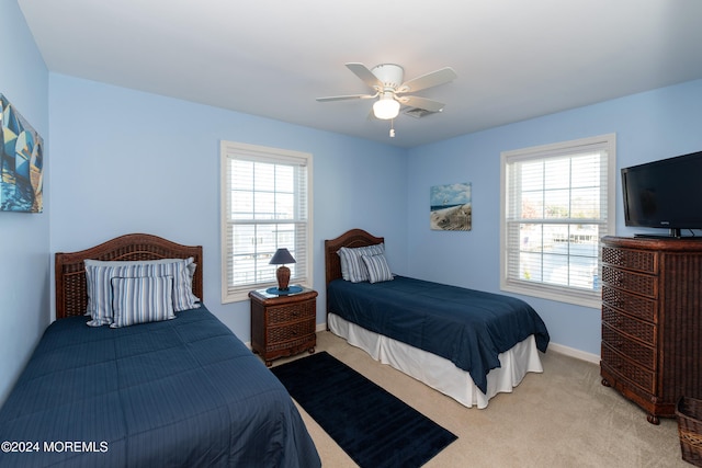 bedroom with multiple windows, ceiling fan, and light colored carpet