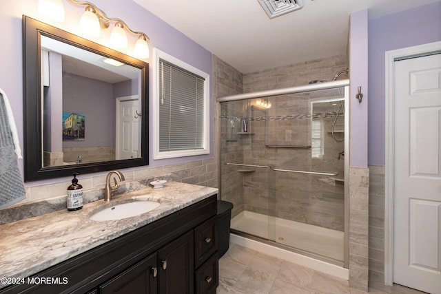 bathroom featuring tile walls, vanity, and an enclosed shower