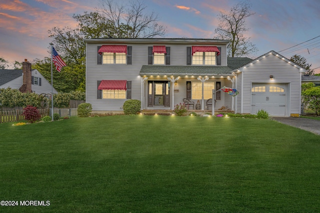 view of front facade with a lawn, a garage, and a porch