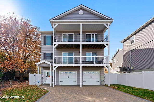 view of front of home with a garage, central AC, and a balcony