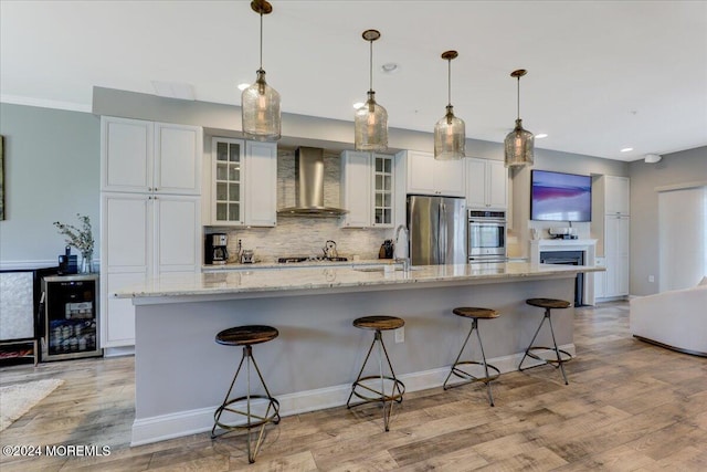 kitchen featuring stainless steel appliances, wall chimney range hood, beverage cooler, and a large island