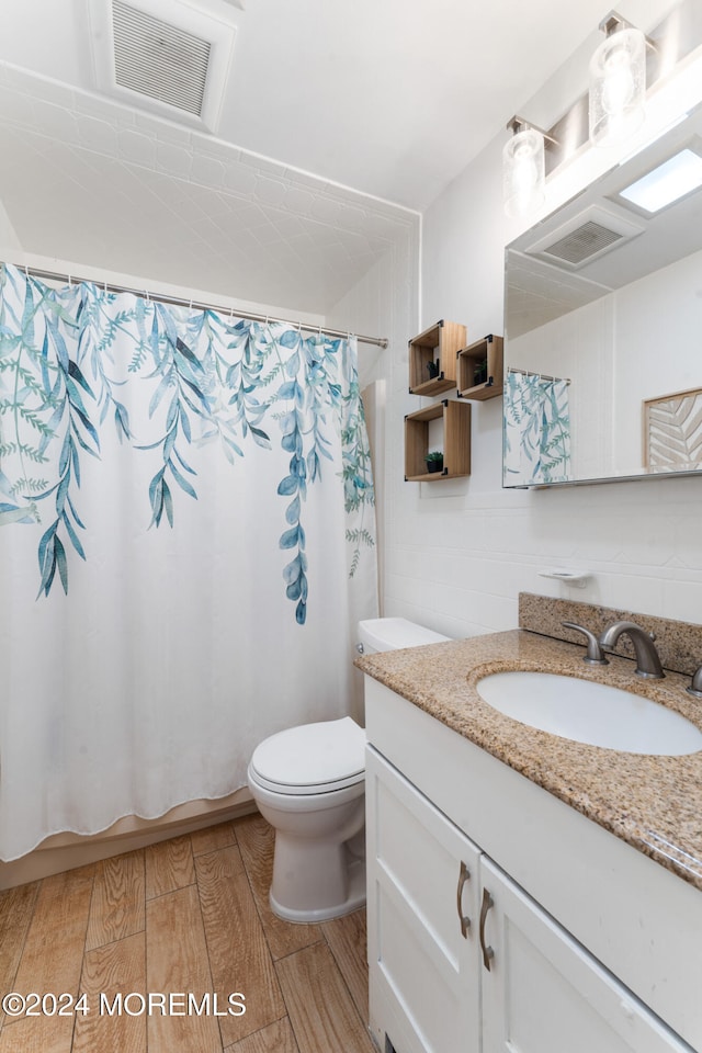 bathroom featuring vanity, hardwood / wood-style flooring, toilet, and walk in shower