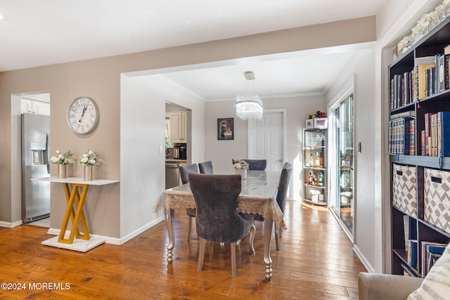 dining room featuring a notable chandelier, wood-type flooring, and ornamental molding