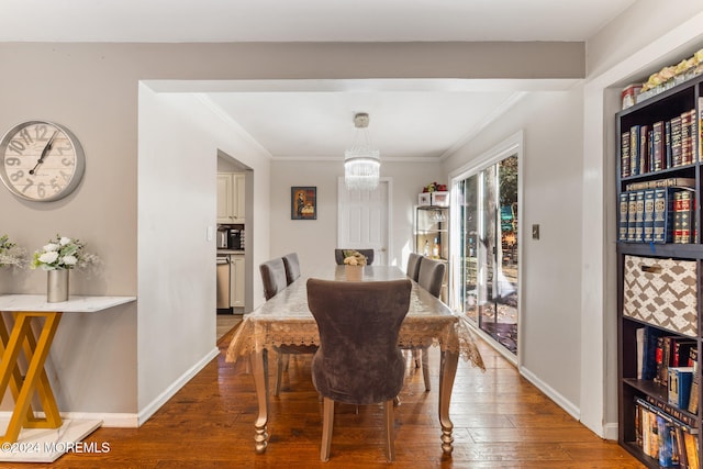 dining area featuring an inviting chandelier, dark wood-type flooring, and crown molding