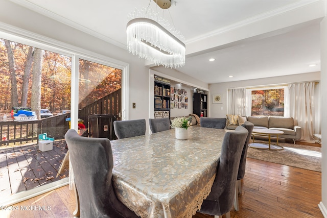 dining space with a healthy amount of sunlight, wood-type flooring, and ornamental molding