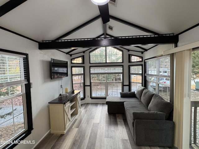 living room with a wealth of natural light and vaulted ceiling with beams