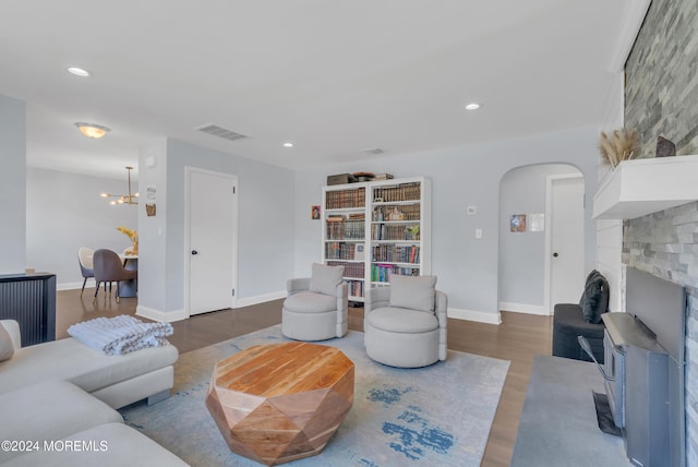 living room featuring a large fireplace, hardwood / wood-style flooring, and a chandelier