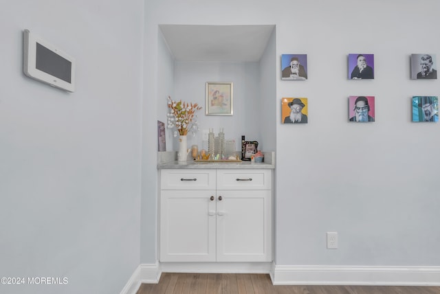 bar featuring white cabinetry and hardwood / wood-style flooring