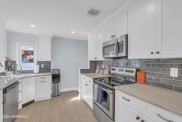 kitchen featuring backsplash, white cabinets, sink, and stainless steel appliances