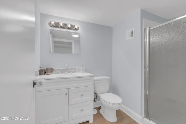 bathroom featuring toilet, vanity, hardwood / wood-style floors, and a shower with door