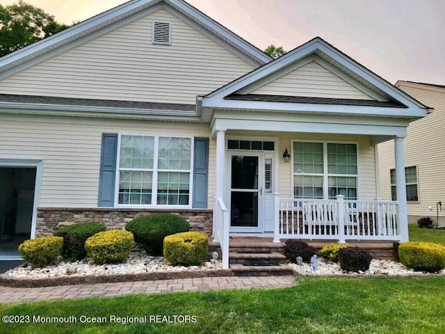 view of front of property with covered porch and a lawn