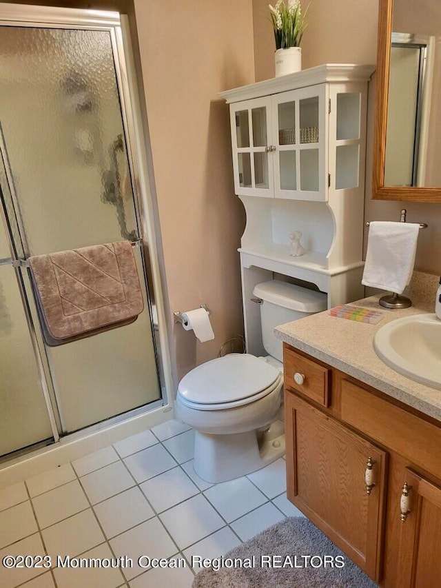 bathroom featuring vanity, toilet, tile patterned flooring, and a shower with door