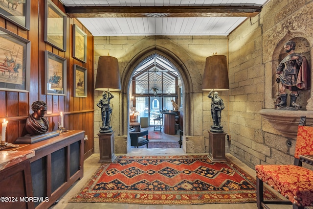 foyer entrance featuring wooden walls, wooden ceiling, and beam ceiling