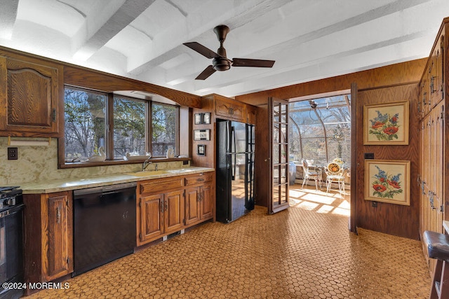 kitchen with wood walls, black appliances, a healthy amount of sunlight, and sink