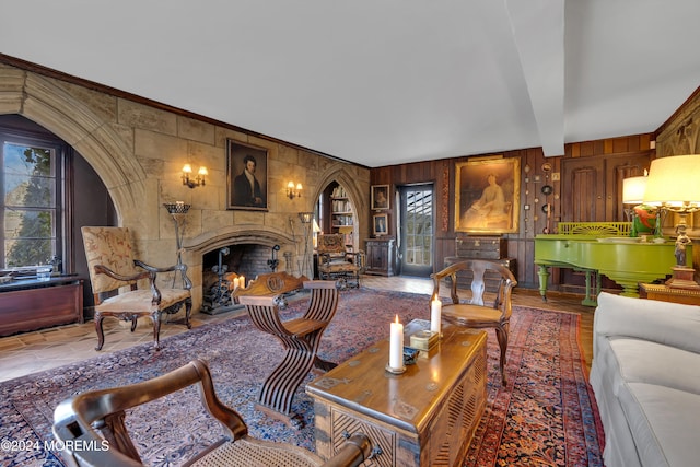 living room with beamed ceiling, a tiled fireplace, and wooden walls