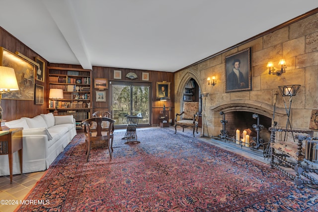 tiled living room featuring a fireplace, built in features, wood walls, and beamed ceiling