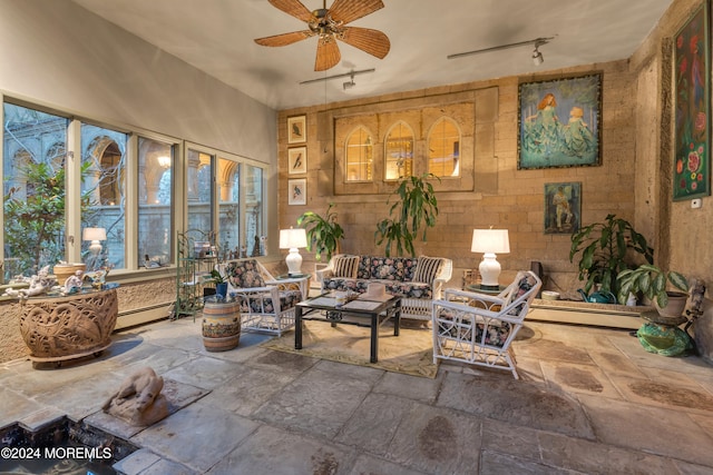 sunroom featuring a baseboard heating unit, rail lighting, and ceiling fan