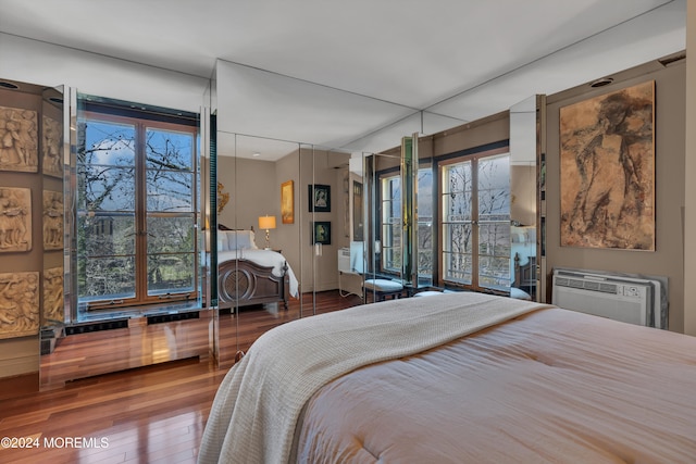 bedroom with hardwood / wood-style floors and a wall mounted AC