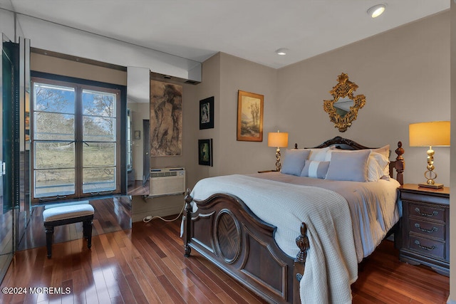 bedroom with a wall mounted AC and dark wood-type flooring