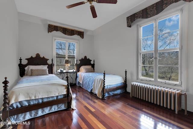 bedroom with radiator heating unit, dark hardwood / wood-style floors, and ceiling fan