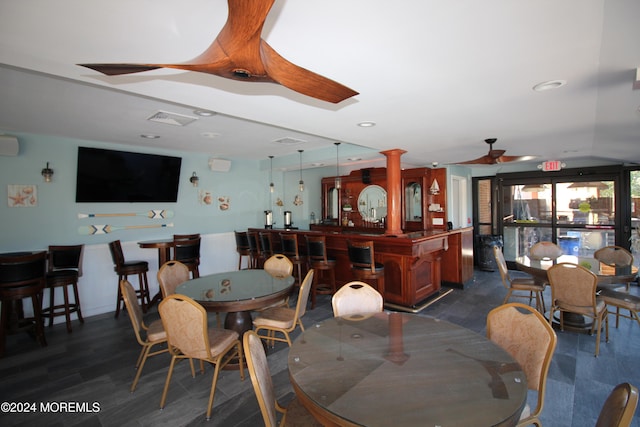 dining space featuring ceiling fan, dark hardwood / wood-style flooring, and bar