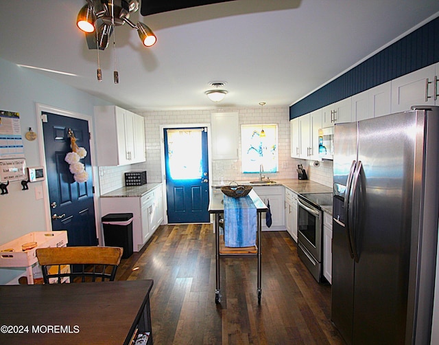 kitchen with appliances with stainless steel finishes, backsplash, sink, white cabinets, and dark hardwood / wood-style floors