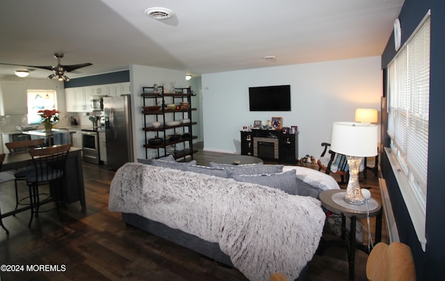 bedroom with multiple windows, stainless steel fridge, dark hardwood / wood-style flooring, and ceiling fan