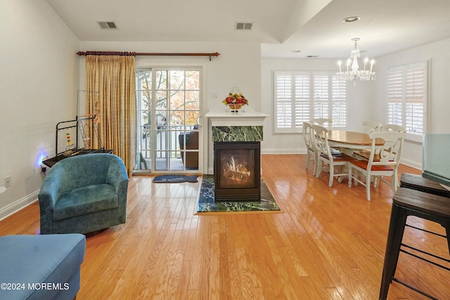 interior space with a wealth of natural light, a premium fireplace, a notable chandelier, and hardwood / wood-style flooring