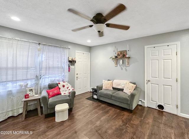 living room featuring a textured ceiling, ceiling fan, and dark wood-type flooring