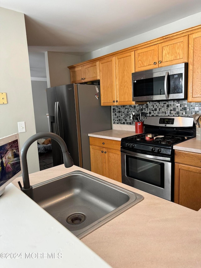 kitchen with sink, appliances with stainless steel finishes, and tasteful backsplash