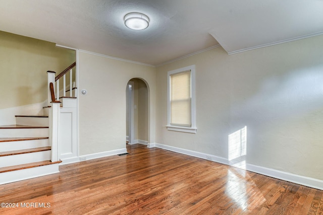 empty room with hardwood / wood-style floors and crown molding