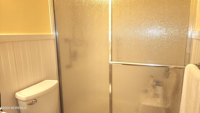 bathroom featuring wooden walls, toilet, and an enclosed shower