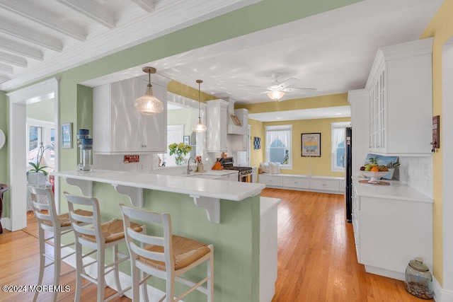 kitchen with stainless steel appliances, kitchen peninsula, a breakfast bar area, white cabinetry, and decorative light fixtures