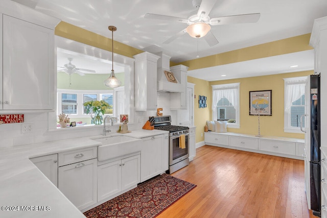 kitchen with white cabinets, custom range hood, stainless steel range with gas stovetop, and sink