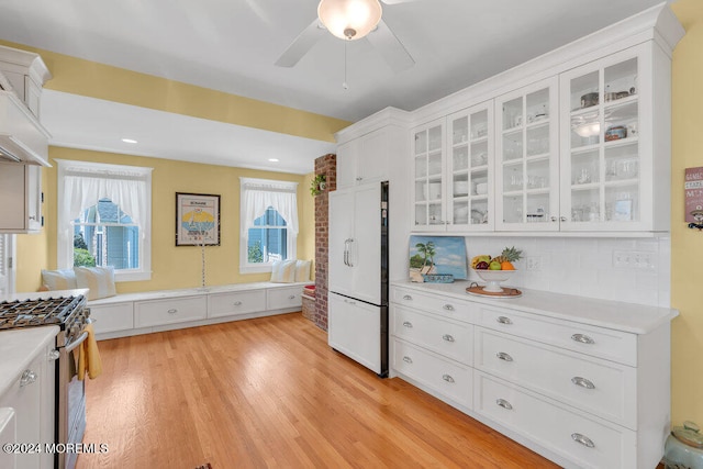 kitchen featuring white cabinets, high end range, ceiling fan, white fridge, and light hardwood / wood-style flooring