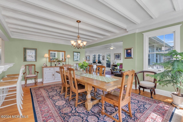 dining area with light hardwood / wood-style floors, ceiling fan with notable chandelier, beam ceiling, and a healthy amount of sunlight