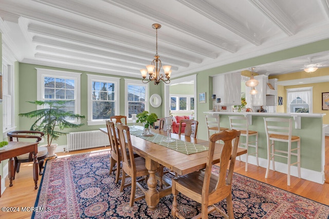 dining area featuring beamed ceiling, ornamental molding, an inviting chandelier, radiator heating unit, and light hardwood / wood-style flooring