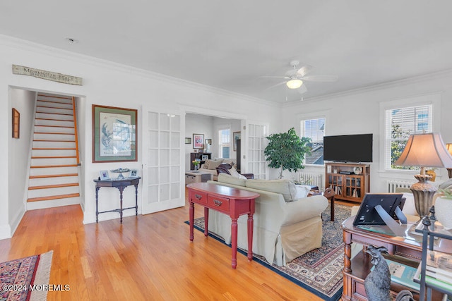 living room featuring french doors, light hardwood / wood-style floors, radiator heating unit, ceiling fan, and crown molding