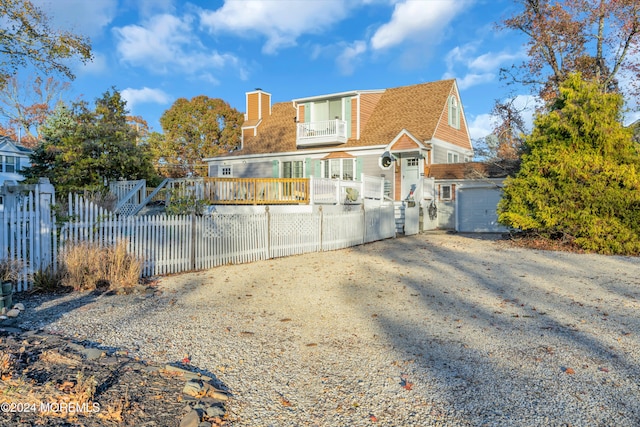 rear view of house featuring a balcony and a garage