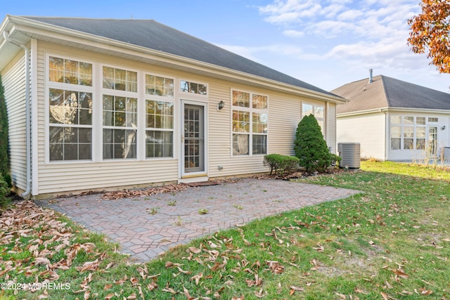 rear view of house featuring a lawn, cooling unit, and a patio area