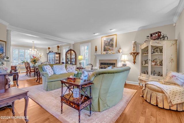 living room with a wealth of natural light, an inviting chandelier, ornamental molding, and light hardwood / wood-style flooring