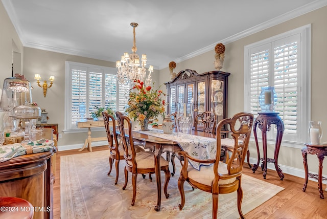 dining area with light wood-type flooring, an inviting chandelier, and ornamental molding