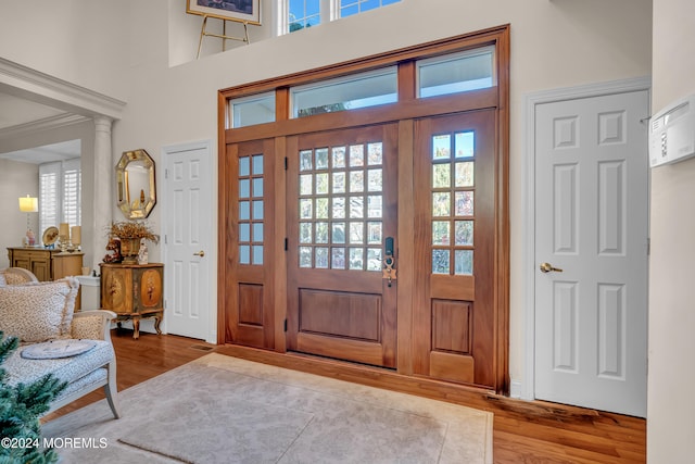 entrance foyer with a high ceiling, decorative columns, hardwood / wood-style flooring, and plenty of natural light