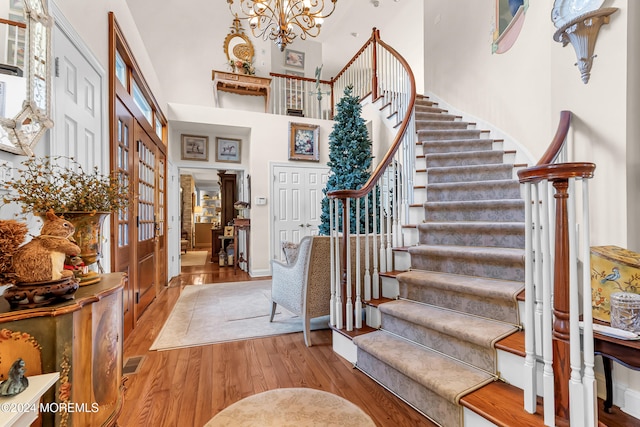 entryway with light hardwood / wood-style flooring, a chandelier, and a high ceiling