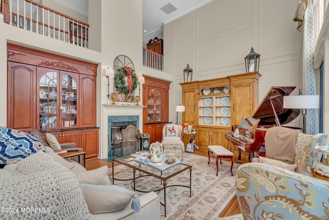 living room featuring light wood-type flooring, a wealth of natural light, a high ceiling, and a premium fireplace