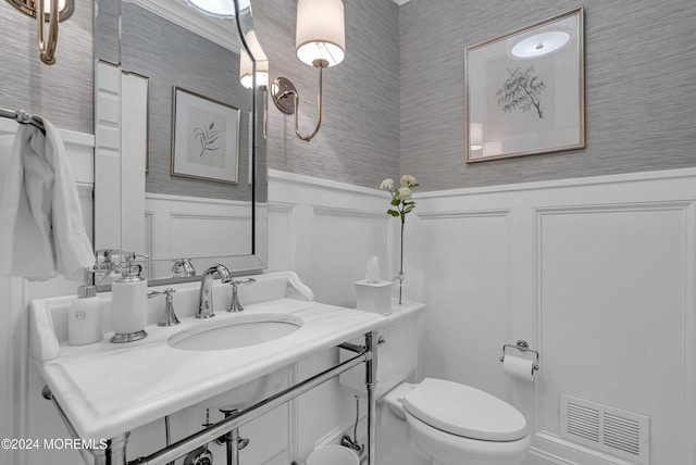 bathroom with toilet, sink, and crown molding